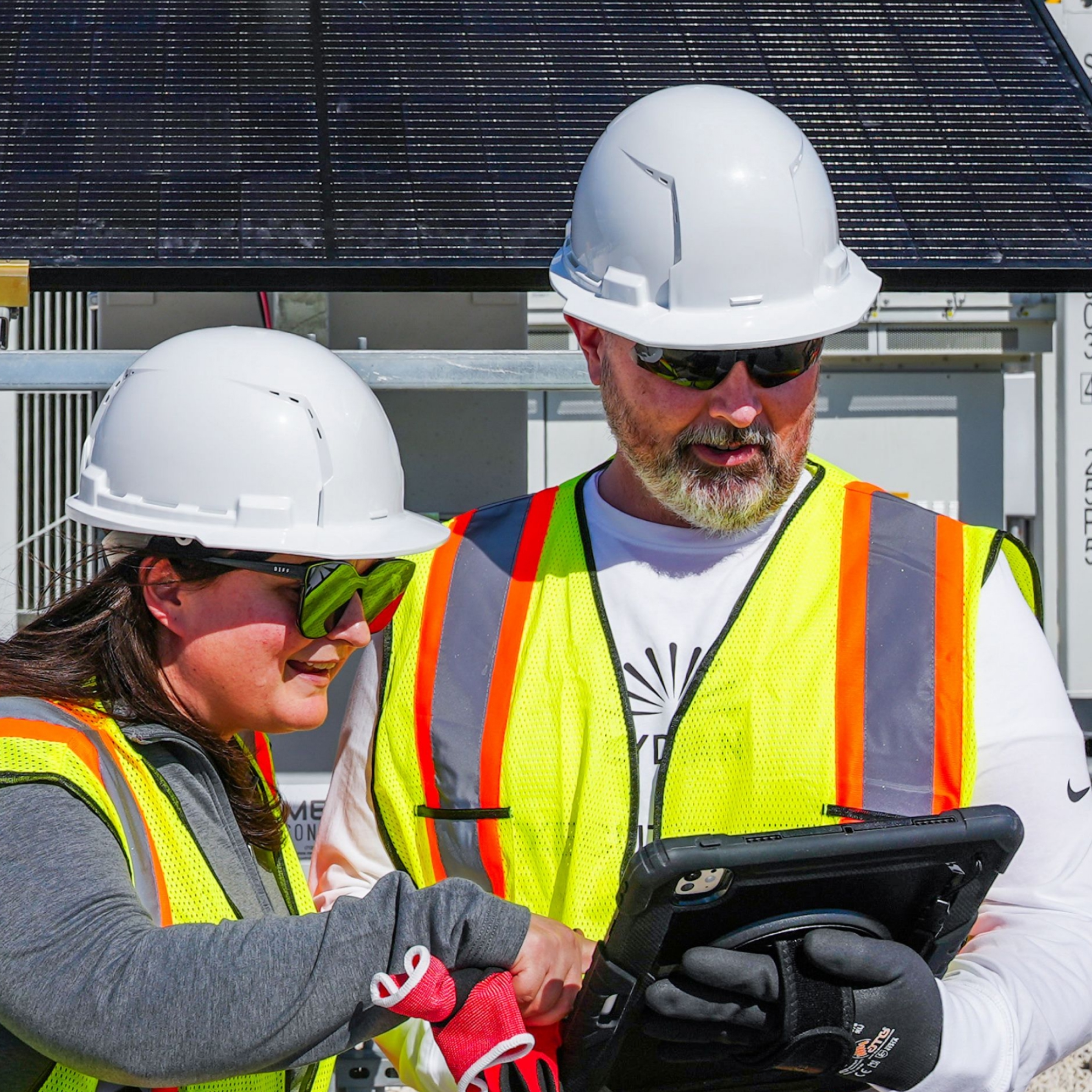 Two Lydian team members reviewing project information on a tablet at an energy facility.