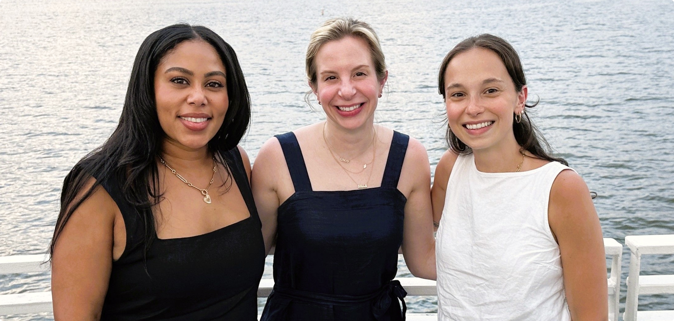 Three Lydian team members at a company social event by the water.